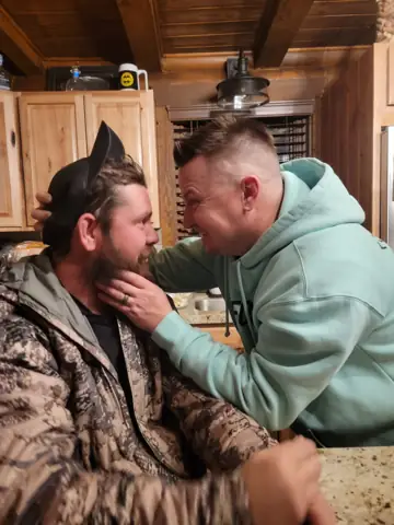 Brett gently holding Carson's face in a kitchen