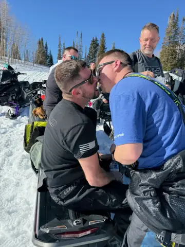 Brett leaning in close to a friend on a snowmobile trip